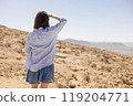 A woman stands confidently in a vast desert, embracing the solitude and natures extraordinary beauty 119204771