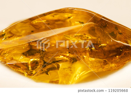 Here is a detailed close up view of a piece of amber laying on a white surface Here is a detailed close up view of a piece of amber laying on a white surface 119205668