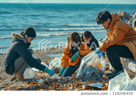 A group of people cleaning up trash on a beach wearing gloves during a sunny day near the ocean A group of people cleaning up trash on a beach wearing gloves during a sunny day near the ocean 119206450
