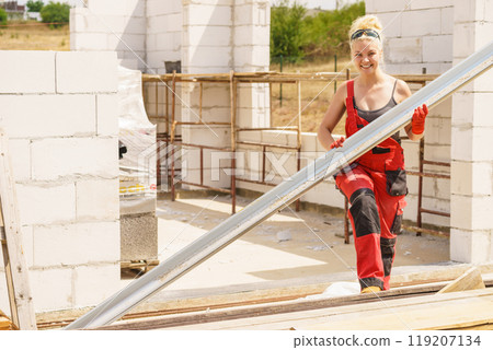 Woman carrying gutter on construction site 119207134