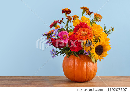 Autumn Floral Arrangement. A vibrant bouquet of autumn flowers in a carved pumpkin vase 119207707