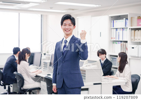 A businessman in a suit making a fist pump in the office 119207809