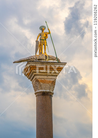 The San Teodoro Column stands majestically in Piazza San Marco, featuring a golden statue of St. Theodore on top, surrounded by vibrant skies that enhance the historic atmosphere. 119208262