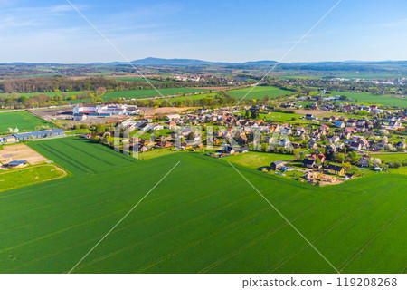 A birds-eye view captures Doubrava Village near Turnov, showcasing its landscape, houses, fields, and roads against the backdrop of a clear sky. Czechia 119208268
