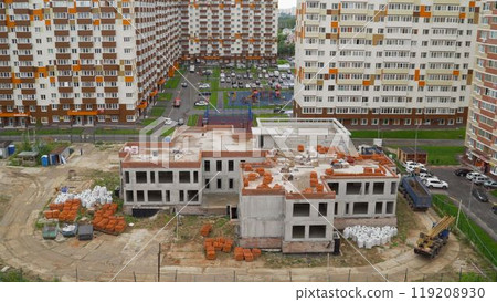 Construction site of a kindergarten in a new residential area with a crane delivering bricks 119208930