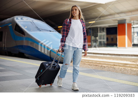 A young woman travels through a busy, modern train station full of energy and anticipation 119209383