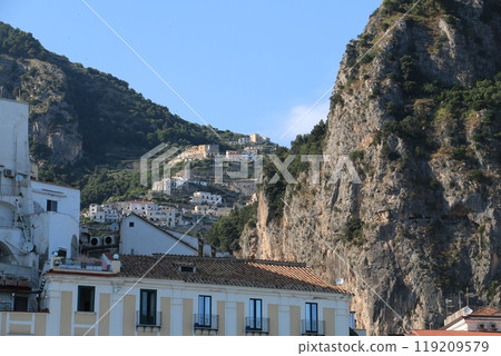 Amalfi, a city of houses lined up on a narrow strip of land surrounded by cliffs Amalfi, a city of houses lined up on a narrow strip of land surrounded by cliffs 119209579