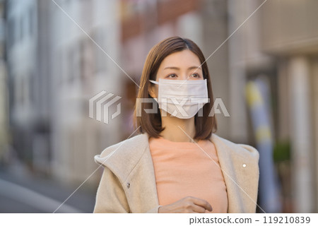 Middle-aged woman walking outdoors wearing a mask 119210839