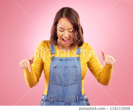 Excited, pointing and young woman in a studio for marketing, promotion or advertising. Shock, surprise and Asian female model with presentation or showing finger gesture isolated by a pink background Excited, pointing and young woman in a studio for marketing, promotion or advertising. Shock, surprise and Asian female model with presentation or showing finger gesture isolated by a pink background 119211699