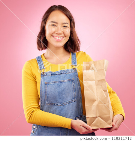 Woman, paper bag and studio portrait for grocery shopping, discount or choice with smile by pink background. Japanese gen z girl, retail customer and package for product, sale or happy for cheap deal 119211712