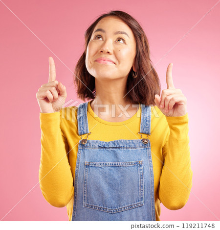 Smile, pointing and happy young woman in a studio for marketing, promotion or advertising. Happiness, confident and Asian female model with presentation finger gesture isolated by a pink background. Smile, pointing and happy young woman in a studio for marketing, promotion or advertising. Happiness, confident and Asian female model with presentation finger gesture isolated by a pink background. 119211748