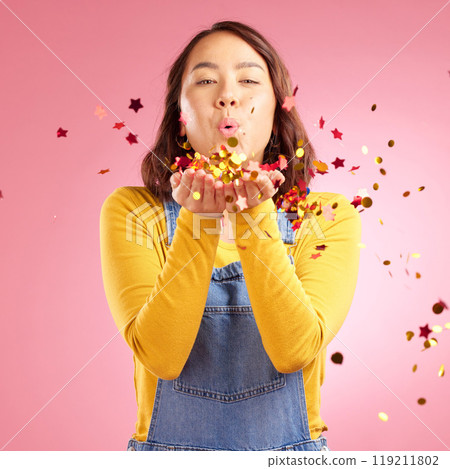 Portrait, celebration and Asian woman blow confetti to celebrate winner, happiness and excited at party event. Studio color, wow and creative Japanese person happy for birthday on pink background 119211802