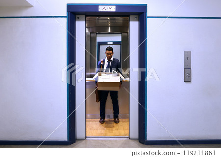 Businessman, fired and sad with box in elevator with unemployment, failure and disappointed or frustrated. Professional, employee and helpless in lift of office building with bag, leaving and stress Businessman, fired and sad with box in elevator with unemployment, failure and disappointed or frustrated. Professional, employee and helpless in lift of office building with bag, leaving and stress 119211861