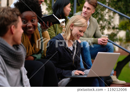 College, friends and laptop on stairs outdoor for research, relax or break on campus with social media. University, students or smile with technology for internet, streaming or learning and diversity 119212006