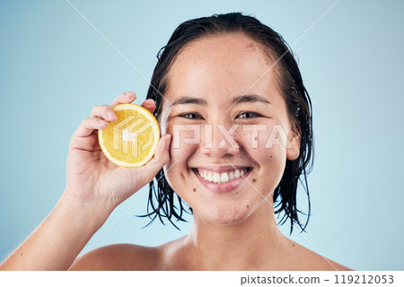 Portrait, smile or happy woman with orange for skincare or beauty in studio on blue background. Results, dermatology shine or Asian person with natural fruits, vitamin c or glowing face for wellness 119212053