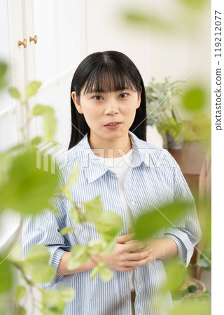 Woman standing by a window indoors Woman standing by a window indoors 119212077