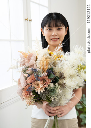 Woman standing indoors with a bouquet of flowers 119212121