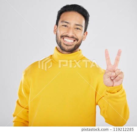 Young man, peace sign and studio portrait with smile, vote and show icon for opinion by white background. Indian fashion model, guy or student with hand, gesture or emoji for voice, freedom or review 119212285