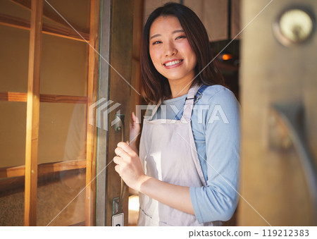 Portrait, waitress and Asian woman at door of restaurant, coffee shop or retail store. Face, smile or confident barista, happy employee or small business entrepreneur welcome to cafe startup in Japan 119212383