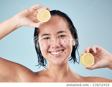 Portrait, smile or happy woman with lemon for skincare or beauty in studio on blue background. Dermatology, shine or Asian person with natural fruits, vitamin c or face glow for wellness or health Portrait, smile or happy woman with lemon for skincare or beauty in studio on blue background. Dermatology, shine or Asian person with natural fruits, vitamin c or face glow for wellness or health 119212418