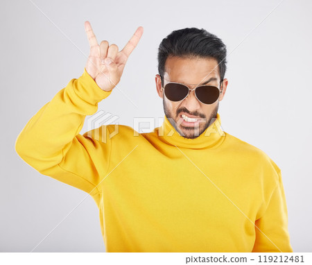 Man, sunglasses and horns sign in studio portrait, rock icon or hand gesture with clothes by white background. Young guy, model and devil fingers for attitude, fashion or crazy with emoji for culture 119212481