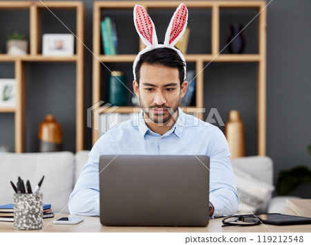 Laptop, bunny ears and business man for Easter in office with decoration for celebration, event and party. Corporate, focus and Asian male person on computer at desk with rabbit headband for holiday 119212548