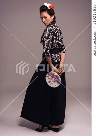 Asian woman, fashion and fan in studio on brown background in confidence, traditional style and elegant. Portrait, Japanese and female person with designer, culture and outfit for heritage. Asian woman, fashion and fan in studio on brown background in confidence, traditional style and elegant. Portrait, Japanese and female person with designer, culture and outfit for heritage. 119212610