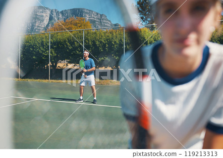 All great things are achieved through hard work and dedication. Shot of a handsome young male tennis player outdoors on the court with a female teammate in the foreground. All great things are achieved through hard work and dedication. Shot of a handsome young male tennis player outdoors on the court with a female teammate in the foreground. 119213313