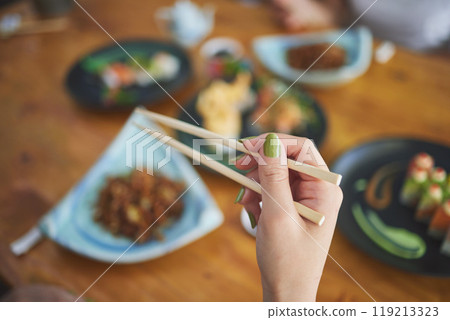 Chopsticks, hand and a person eating food at a restaurant for nutrition. Closeup of a hungry woman with wooden sticks or utensil for dining, Japanese culture and cuisine on diet with sushi on menu Chopsticks, hand and a person eating food at a restaurant for nutrition. Closeup of a hungry woman with wooden sticks or utensil for dining, Japanese culture and cuisine on diet with sushi on menu 119213323