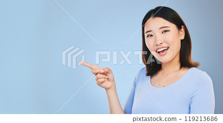 Asian woman, point and studio portrait with space, mockup and happy for promotion by blue background. Japanese student, girl and smile for review, opinion or feedback with choice, decision and sign Asian woman, point and studio portrait with space, mockup and happy for promotion by blue background. Japanese student, girl and smile for review, opinion or feedback with choice, decision and sign 119213686