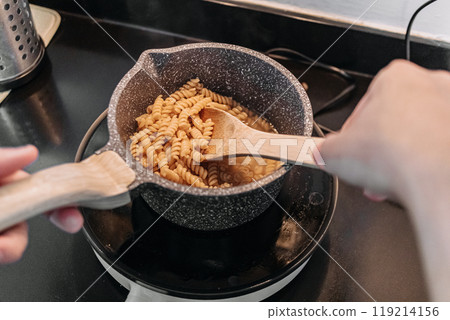 Man cooking homemade pasta in his small apartment kitchen. Man cooking homemade pasta in his small apartment kitchen. 119214156