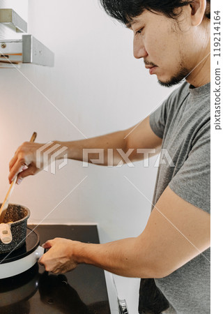 Man cooking homemade pasta in his small apartment kitchen. 119214164