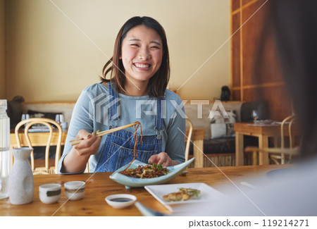 Japanese, food and woman at a restaurant eating for dinner or lunch meal using chopsticks and feeling happy with smile. Plate, date and person enjoy Asian cuisine, noodles or diet at a table 119214271