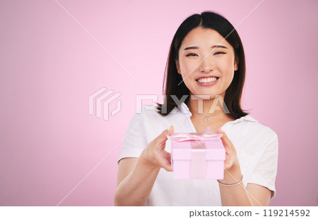 Gift, Asian and portrait of woman giving present box happy for celebration isolated in a studio pink background. Giveaway, ribbon and person with happiness for surprise or prize package with smile 119214592