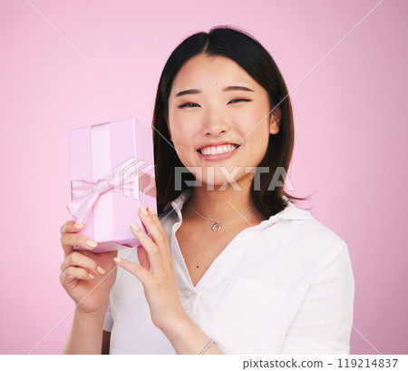 Giveaway, Asian and portrait of woman giving present box happy for celebration isolated in a studio pink background. Gift, ribbon and person with happiness for surprise or prize package with smile 119214837