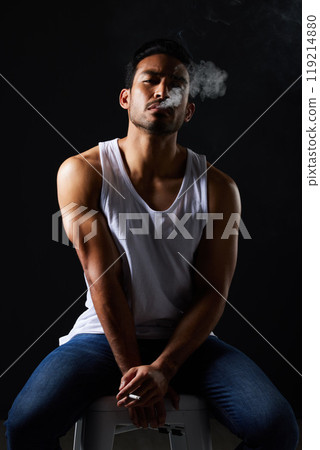 Smoking portrait, sexy man and chair in studio in fitness, beauty aesthetic and strong sensual fashion. Art, body and male model with muscle, cigarette and jeans on black background in dark lighting. 119214880