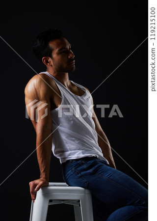 Sexy, thinking and man on chair in studio with fitness inspiration, strong aesthetic and fashion. Art, body and healthy male model sitting on black background, bodybuilder muscle in dark lighting. 119215100