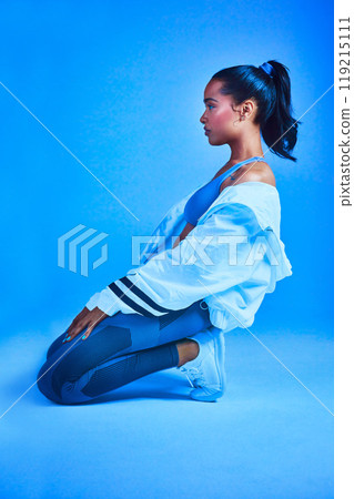 At the mercy of the fitness gods. Full length shot of an attractive young female athlete posing on her knees against a blue background. At the mercy of the fitness gods. Full length shot of an attractive young female athlete posing on her knees against a blue background. 119215111