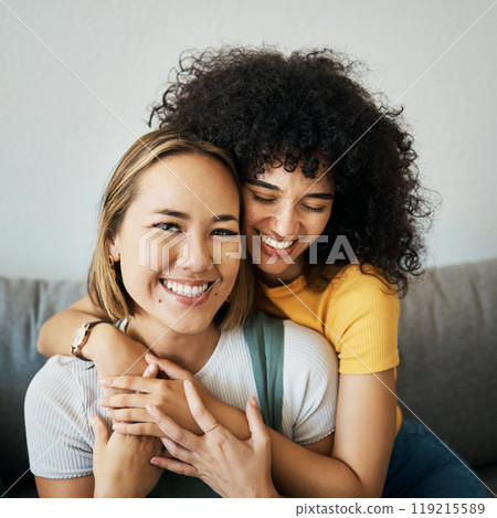 Lesbian, couple and portrait of hug on sofa in home, living room or apartment with love, support and happiness. Lgbt, women and relax together with pride, confidence and smile on face in house 119215589