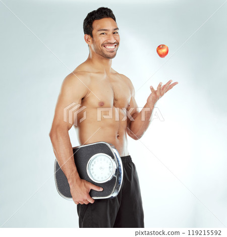 Wellness, scale and happy man portrait with apple throw in studio for health, diet or Weight loss motivation on white background. Nutrition, detox or face of Japanese model fruit, balance or progress 119215592