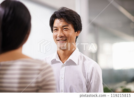 Happy, cooperation and businessman in conversation at office with feedback on project collaboration. Japanese, employee and talking to woman with discussion of ideas, development or social teamwork 119215815