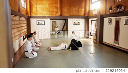 Students, aikido sensei or teaching Japanese martial arts in dojo for practice, body movement or self defense. Combat demonstration, group of people or training workout for black belt fighting class 119216034