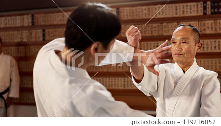 Aikido class, student and sensei for martial arts, learning and advice for combat at training, gym and dojo. Japanese people, block and sports with fight, workout or fitness for zen, conflict or club 119216052