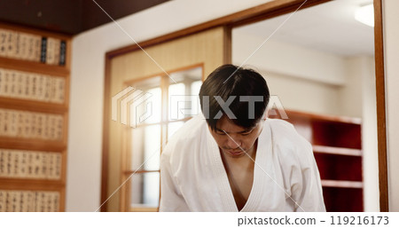Aikido student, bow or man in dojo to start practice, discipline or self defense education in Japan. Black belt master greeting, athlete learning respect or ready in fighting class or aikido training 119216173