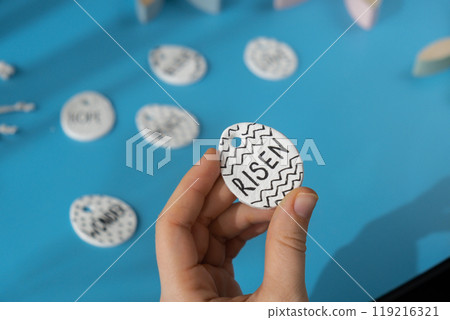 Master class writing word RISEN on EASTER clay egg Unrecognizable artist do it yourself air dry clay crafts for Easter holiday. Decoration gift idea Handmade children craft. Step by step instruction 119216321