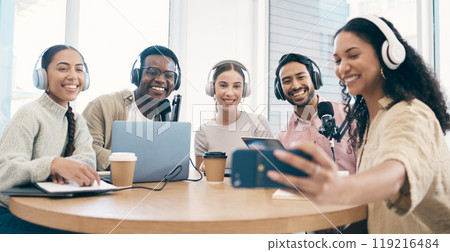 Podcast, smile and group selfie of friends together bonding, live streaming and people recording broadcast in studio. Happy team of radio hosts take picture at table for social media or collaboration 119216484