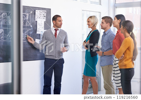 Creative man, chalkboard and presentation with team for storyboard, development or meeting at office. Male couch talking to group of employees for project planning, production or startup at workplace 119216560