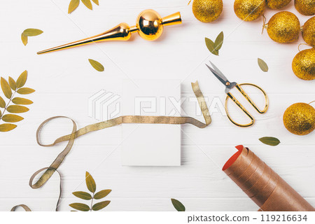 A white card with a gold ribbon is sitting on a table with scissors 119216634