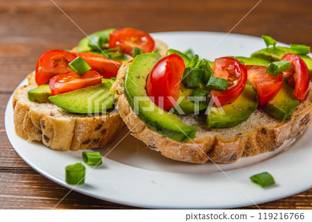 Avocado toast topped with tomato and green onion on a slice of carrot bread 119216766
