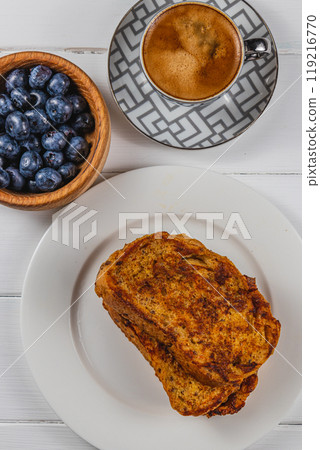 French toast on a white plate with blueberries and coffee for breakfast 119216770